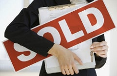 Person holding sold sign