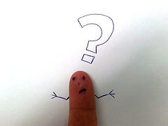 Finger with face drawn on it and drawing of question mark above